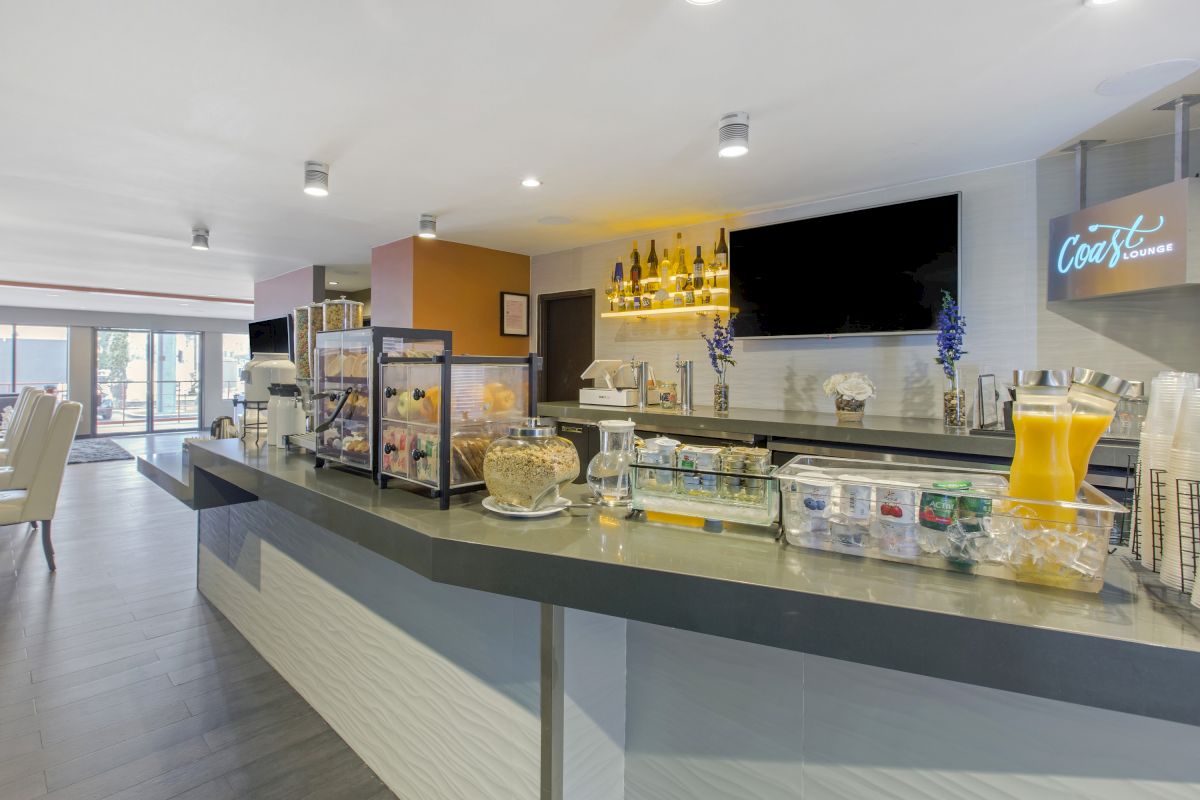 The image shows a sleek food counter with various breakfast items, including cereal, juice, and condiments, in a contemporary dining area.