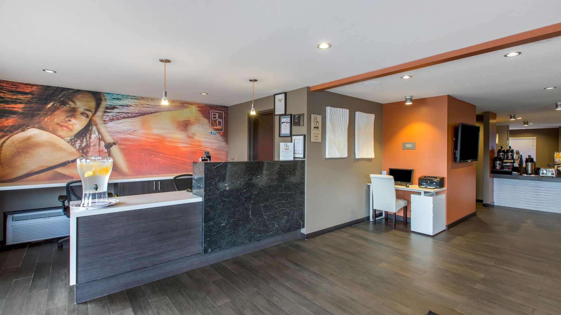 A modern reception area with a large wall mural, sleek desk, bar, computer station, framed art on walls, and minimalist decor, ending the sentence.