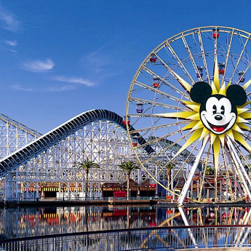 The image showcases a theme park with a large Ferris wheel featuring a smiling character, roller coasters, and other amusement rides under a bright sky.