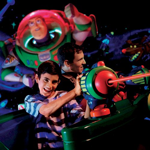 Two people are enjoying an interactive ride featuring Buzz Lightyear, aiming laser guns at targets in a space-themed environment.